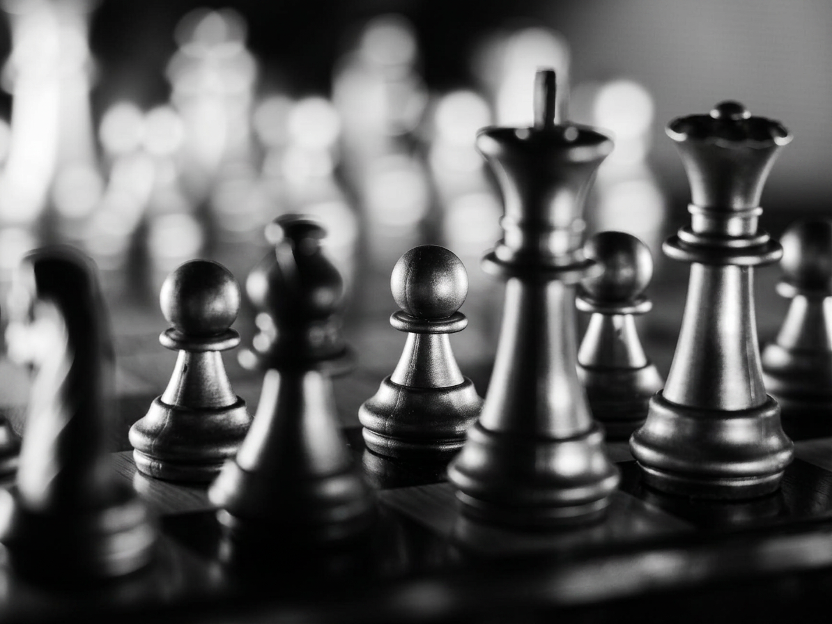 A full company of dark chess pieces assembled on the board, the back rank fading into light